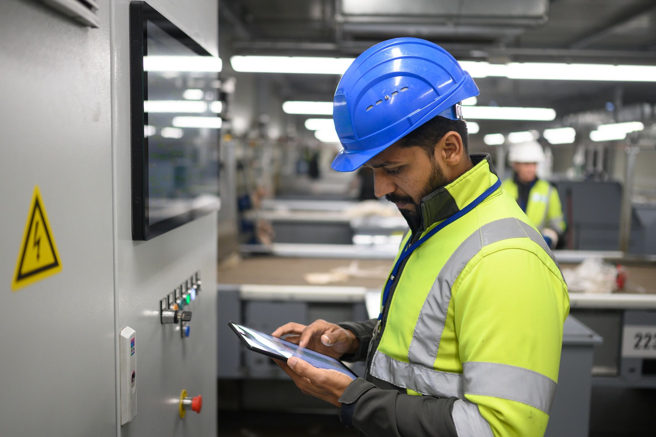 Electrician using a tablet in an industrial facility